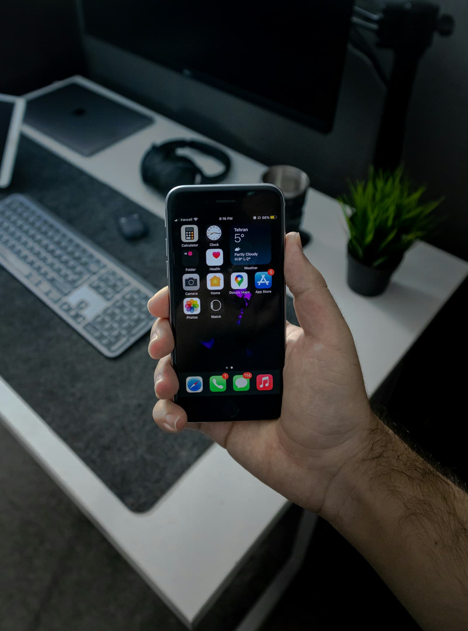 Hand holding a smartphone above a desk