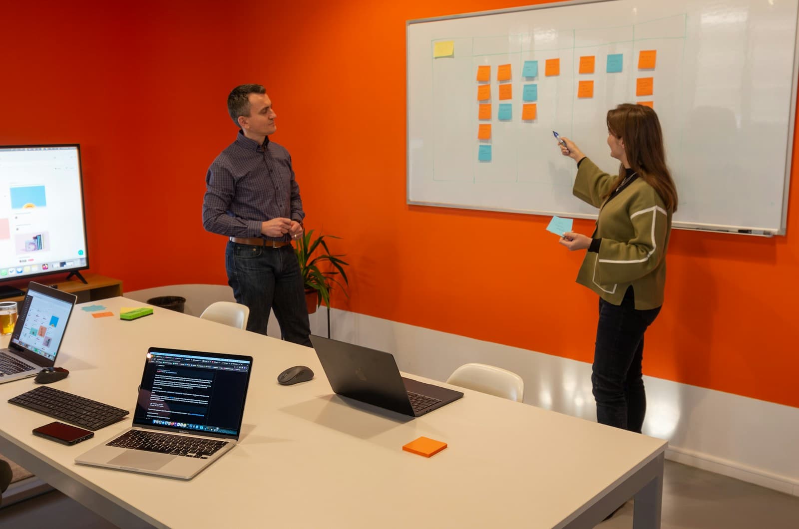 Two people planning work on a whiteboard of sticky notes